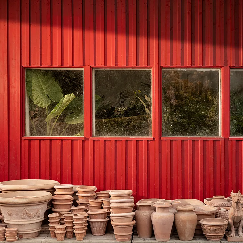 Terracotta-Gefäße gestapelt vor einer roten Holzfassade