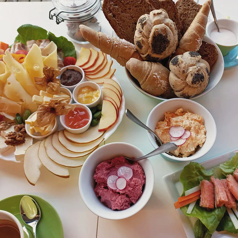 Frühstücksplatte mit Gebäck, Käse, Äpfeln und Aufstrichen