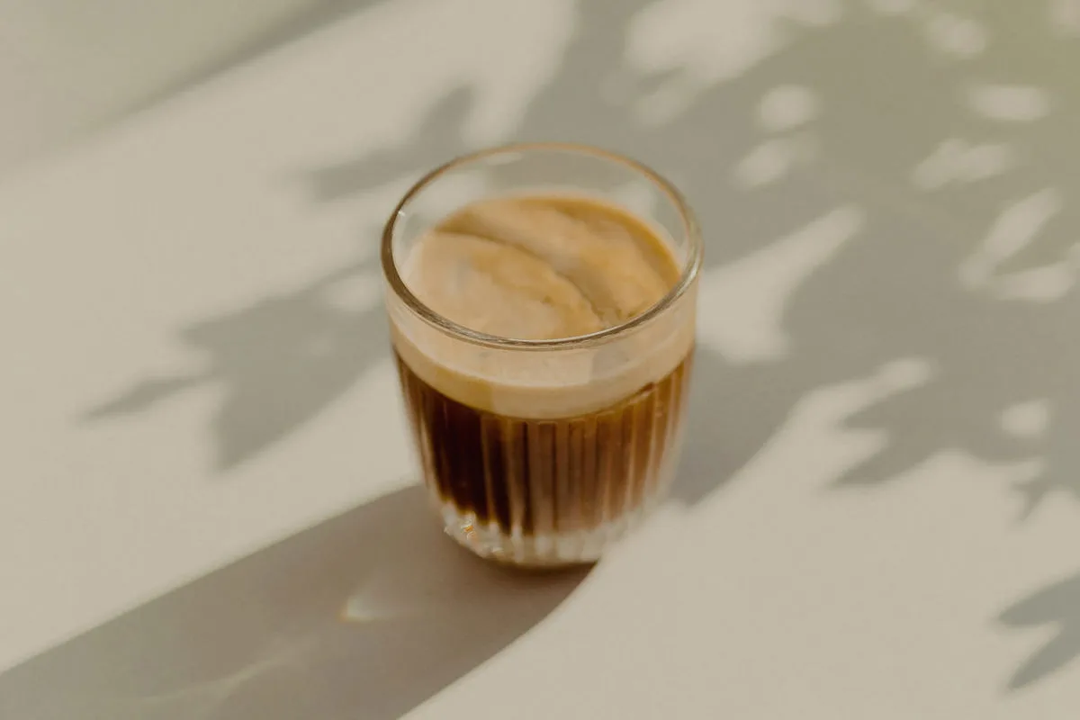 Kaffee im Glas mit Schatten von Blättern