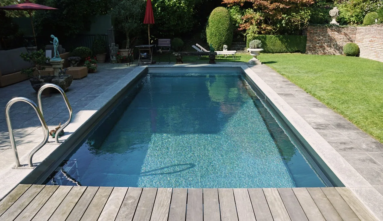 Pool mit Holzdeck und Natursteinrand in einem Garten
