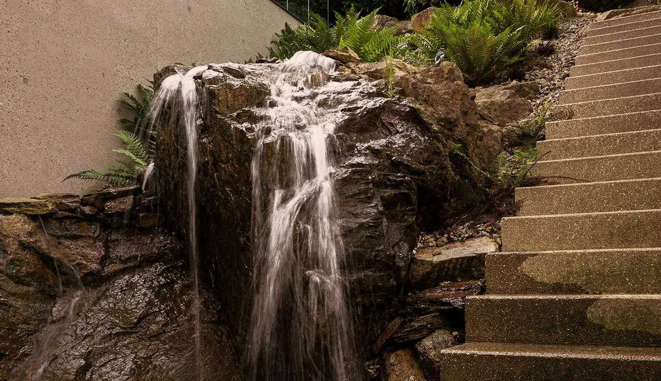 Wasserfall über einen Felsblock neben einer Steintreppe